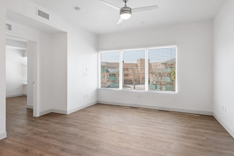 a bedroom with a large window and hardwood floors